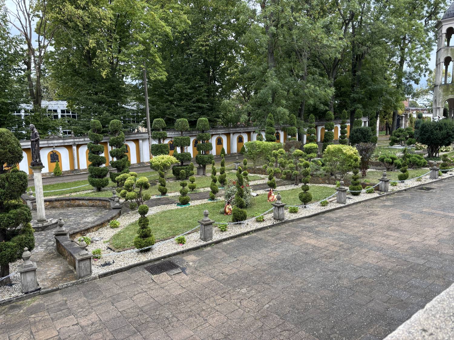 Panorama formowanego ogrodu z licznymi kulami i spiralami topiary